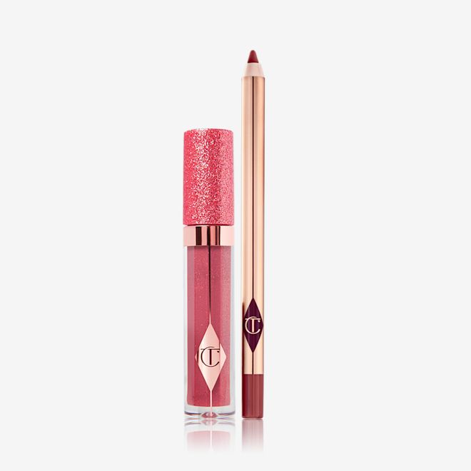 Pillow Talk Jewel Lip Kit in Walk of No Shame closed Shimmery lip gloss in a berry-pink shade in a glass tube with a glittery lid with an open lip liner pencil in a dark berry-pink shade.