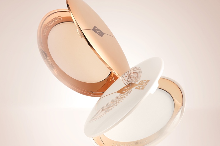 Two, open, setting powder compacts with mirrored-lids and white and gold-coloured packaging.