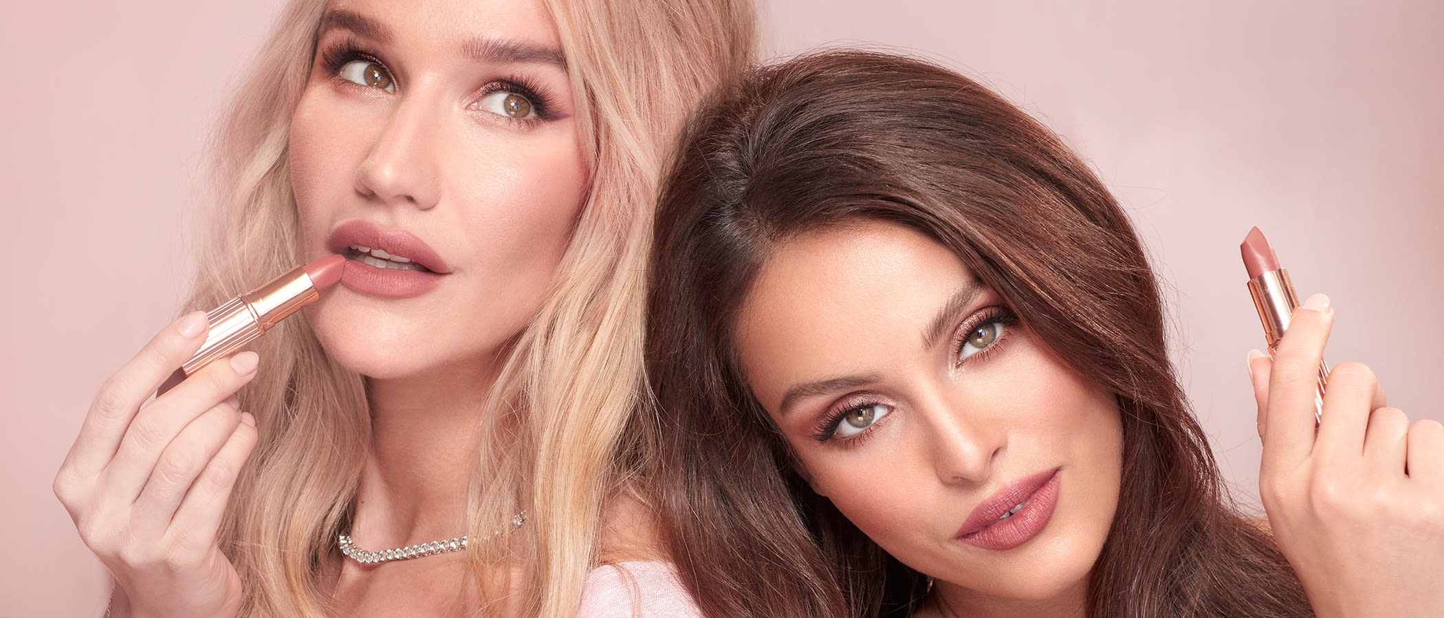 Sofia Tilbury with a brunette model, with both wearing glowy nude pink, make while holding nude pink lipsticks.