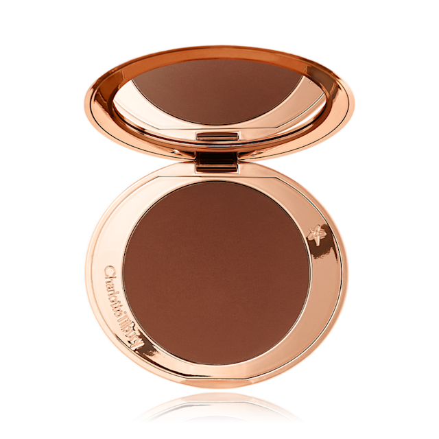 An open bronzer compact with a mirrored-lid in a rich chocolate brown shade, perfect for deep skin tones.