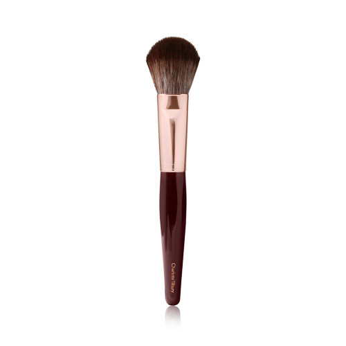 A bronzer and blush brush with soft bristles and rose gold and dark crimson handle.