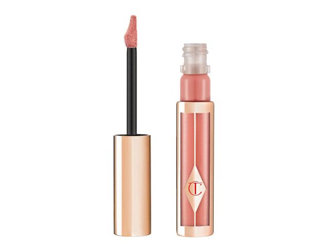 An open liquid lipstick in a bright pink shade with golden-coloured packaging and its doe-foot applicator next to it. 