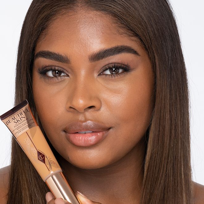 Beautiful Skin Foundation in 11W on deep-tone model Dark-tone brunette model wearing glowy, skin-like foundation with a satin finish with nude lipstick and subtle eye makeup.