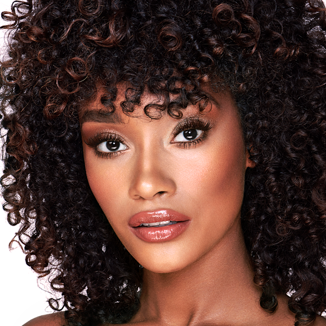 The Golden Goddess look on deep-tone model A deep-tone model with brown eyes wearing smokey brown eye makeup with warm bronze and pink blush, and glossy terracotta lips.