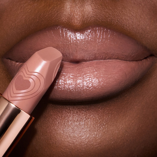 Deep skin model close up of lips wearing a warm caramel-nude lipstick with a satin finish