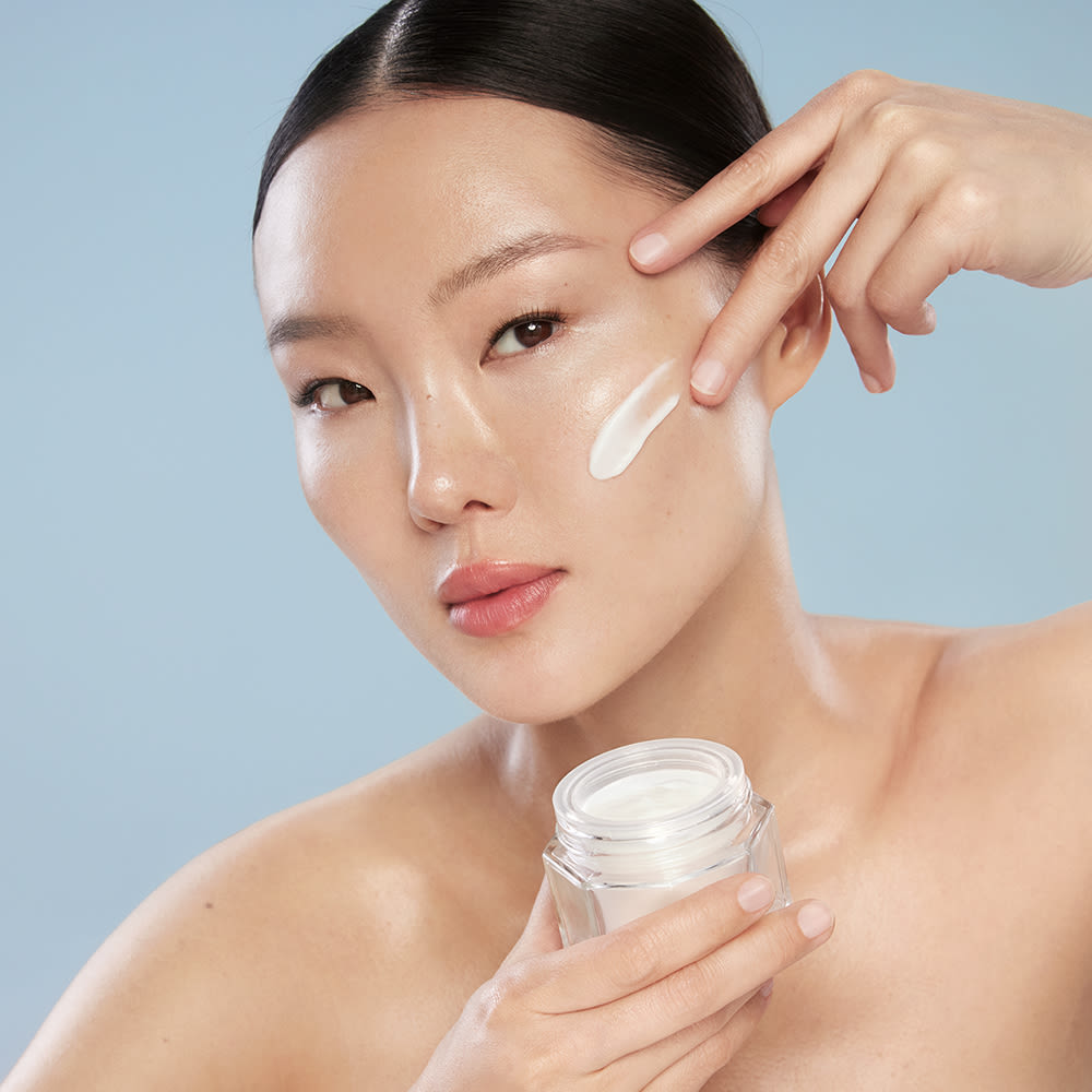 Gia trägt die Gel-Feuchtigkeitscreme Charlotte's Magic Water Cream für unmittelbare Feuchtigkeitsversorgung auf ihre Wangen auf