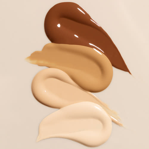 Swatches of four liquid foundations in dark brown, sandy brown, light beige, and light yellow-cream colour.