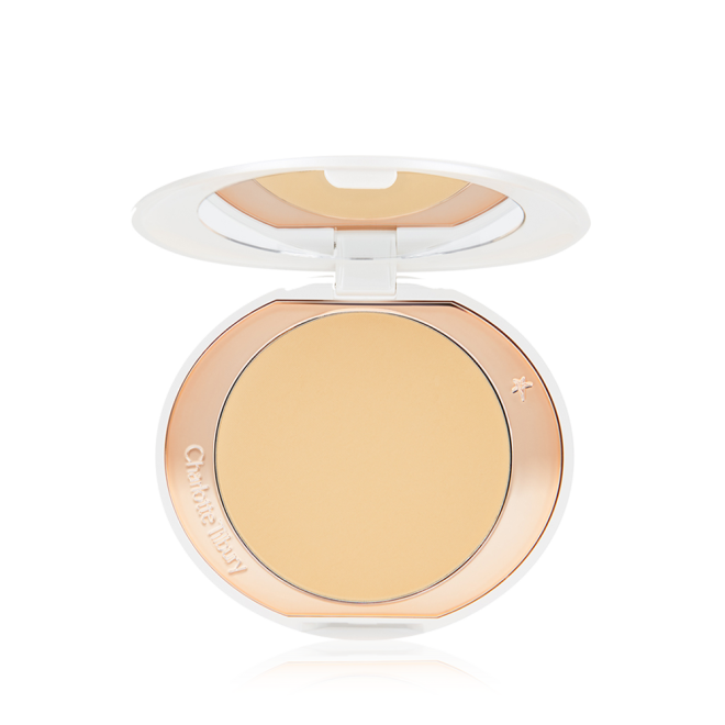 An open, setting powder compact with a mirrored-lid and white and gold-coloured packaging.