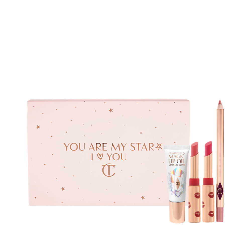 Two open lipsticks in burnt orange and bright pink colours with gold-coloured tubes with red-coloured kiss pattern all over, an open lip liner pencil in nude pink, and lip oil in a white-coloured tube with gold-coloured lids, along with a light pink-coloured makeup sleeve with text in rose gold on it that reads, 'you are my star. I love you'