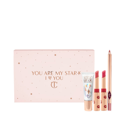 Two open lipsticks in burnt orange and bright pink colours with gold-coloured tubes with red-coloured kiss pattern all over, an open lip liner pencil in nude pink, and lip oil in a white-coloured tube with gold-coloured lids, along with a light pink-coloured makeup sleeve with text in rose gold on it that reads, 'you are my star. I love you'
