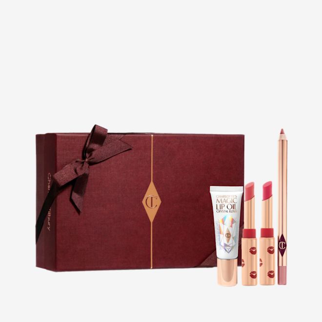 Lucky Lip Secrets Box-Gift-Box Two open lipsticks in burnt orange and bright pink colours with gold-coloured tubes with red-coloured kiss pattern all over, an open lip liner pencil in nude pink, and lip oil in a white-coloured tube with gold-coloured lids, along with a light pink-coloured makeup sleeve with text in rose gold on it that reads, 'you are my star. I love you'