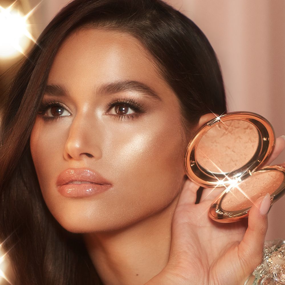 Modèle portant un maquillage Hollywood Glow et tenant le nouvel highlighter de Charlotte.