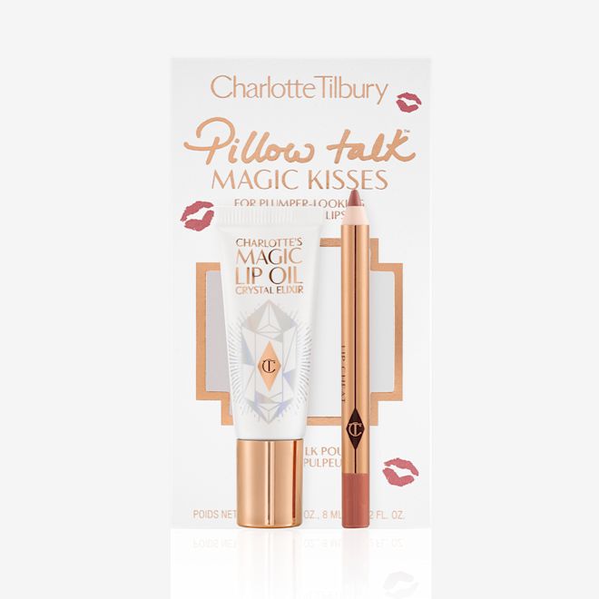 Pillow Talk Magic Kisses kit displayed Lip oil in a white-coloured tube with a gold-coloured lid along with a lip liner pencil in a nude pink shade and the packaging box behind them with text on it that reads, 'Pillow Talk Magic Kisses'