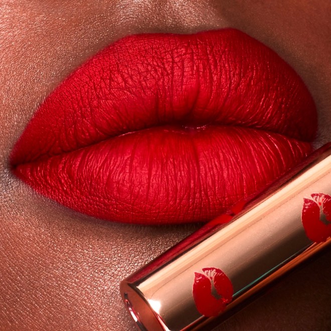 Lips close-up of a deep-tone model wearing poppy red lipstick with a matte finish.