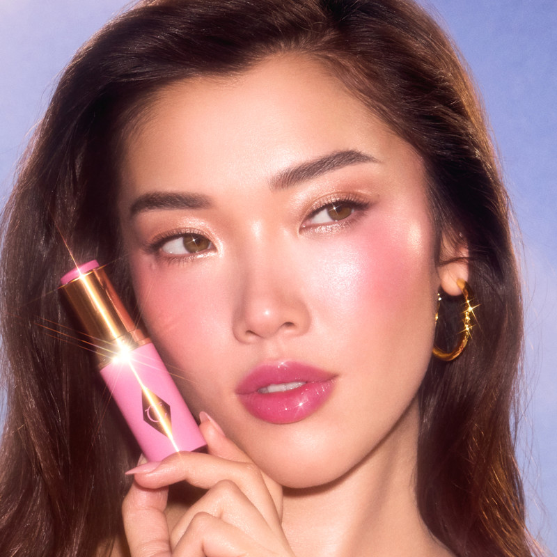 Model wears Unreal Blush Healthy Glow Stick in Pretty Glow