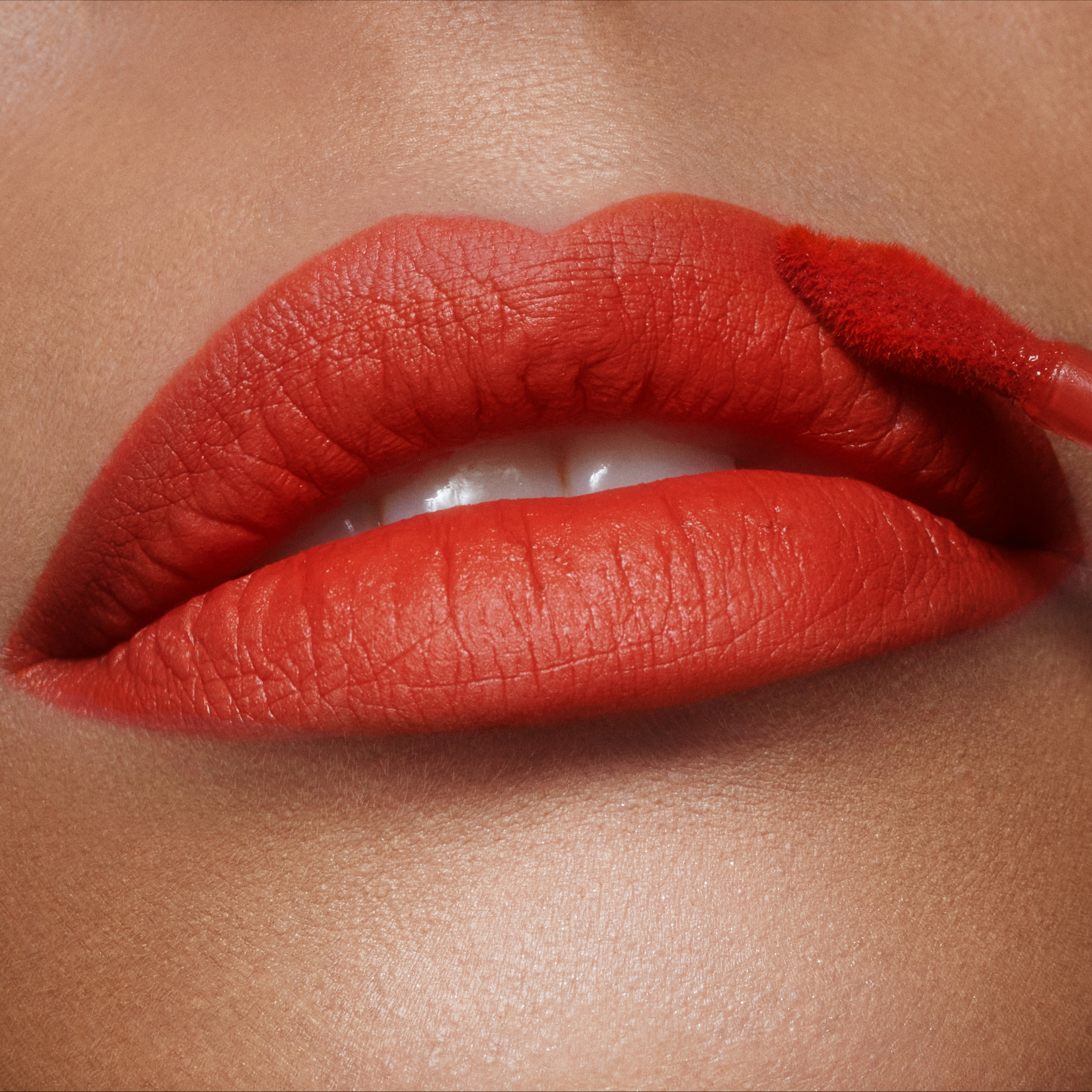 Model wearing Airbrush Flawless Lip Blur liquid lipstick in Flame Blur, a hot orange-red