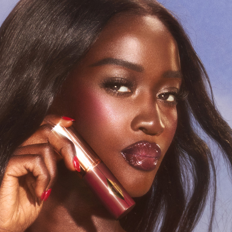 Model wears Unreal Blush Healthy Glow Stick in Berry Glow