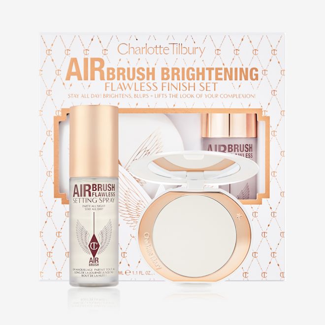 Airbrush Brightening Flawless Complexion Perfecting Set with box displayed Setting spray in a clear bottle with a gold-coloured lid with a brightening setting powder compact in gold-packaging with a mirrored-lid along with a white and pink-coloured packaging box.
