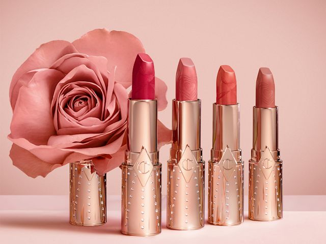 Four, open, nude lipsticks in shades of brown, peach, pink, and red with gold-coloured tubed with rhinestones studded.