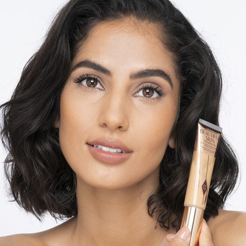 Medium-light-tone brunette model wearing glowy, skin-like foundation with a fresh, satin finish with a nude lipstick, and subtle eye makeup.