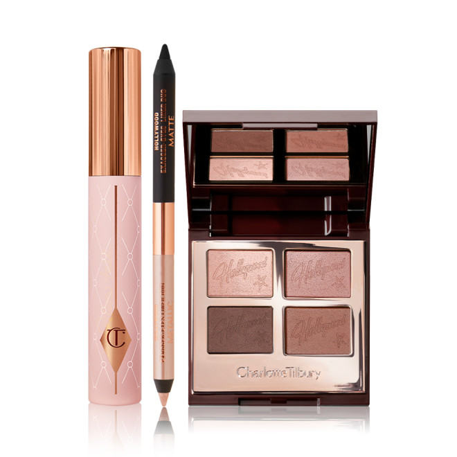 Mascara in a nude pink tube with a gold-coloured lid, an open, double-sided eyeliner pen in black and soft champagne-beige, and an open, mirrored-lid quad eyeshadow palette with matte and shimmery shades in gold and brown.
