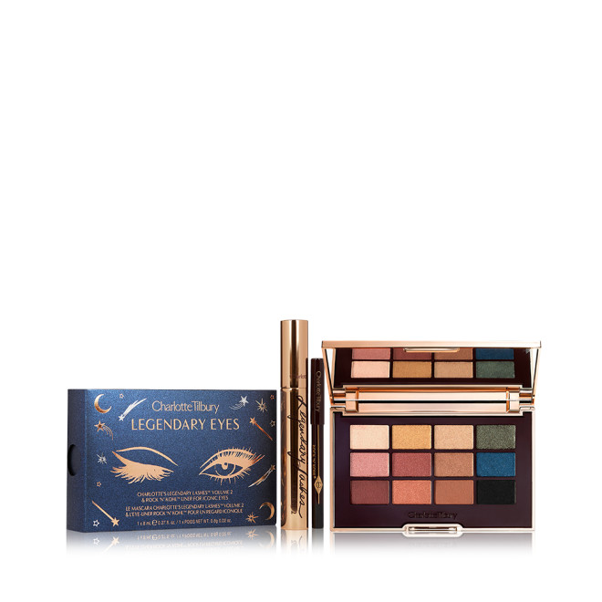 An open, mirrored-lid eyeshadow palette with nude brown, green, blue, black, gold, and pink shades with a black-coloured eyeliner pencil and mascara, with a midnight blue-coloured packaging box. 