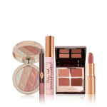 An open, pressed powder highlighter compact in various shades of pink and gold for cool-tone complexions, eyeshadow stick in nude pink, black mascara, quad eyeshadow palette in shades of brown, and a nude pink matte lipstick. 