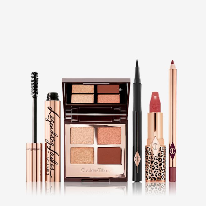 Sofia Tilbury Bundle Pack displayed An open mascara tube with its applicator next to it, an open, mirrored-lid quad eyeshadow palette with matte and shimmery brown and golden shades, an open eyeliner pen, a matte lipstick in terracotta-red with a matching lip liner pencil.