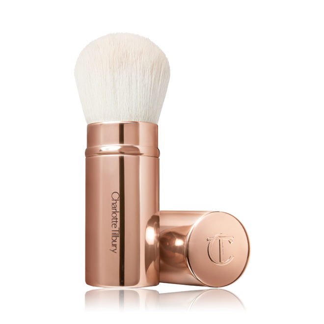 A face blending brush with white bristles in rose gold packaging.