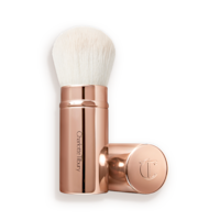 A face blending brush with white bristles in rose gold packaging with the cap beside it.