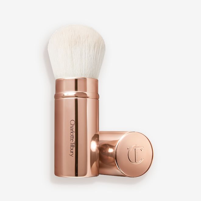 The Air Brush Bronzing Brush opened A face blending brush with white bristles in rose gold packaging with the cap beside it.