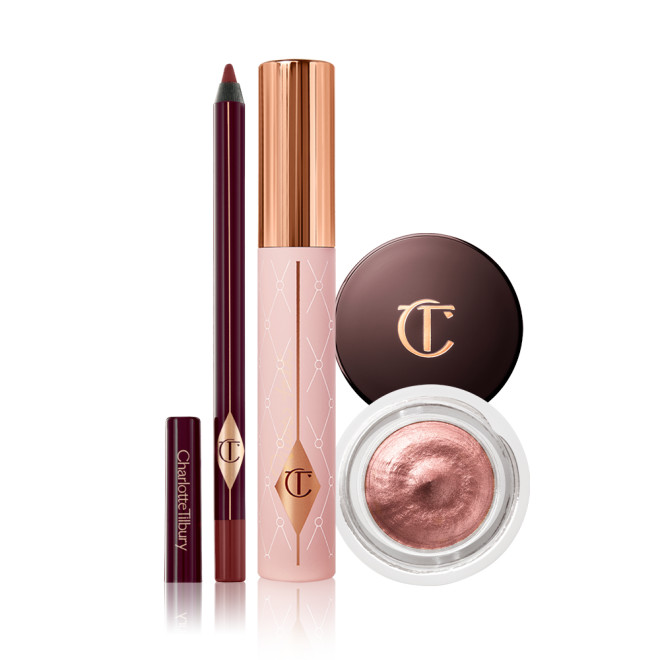 An open eyeliner pencil in a berry-brown shade, mascara in a nude pink tube with a gold-coloured lid, and cream eyeshadow in a rose gold shade in a glass pot with a dark-brown-coloured lid.