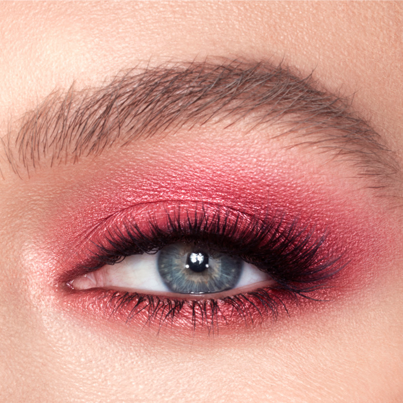 Eye close-up of a fair-tone model with blue eyes wearing bright pink eye makeup. 
