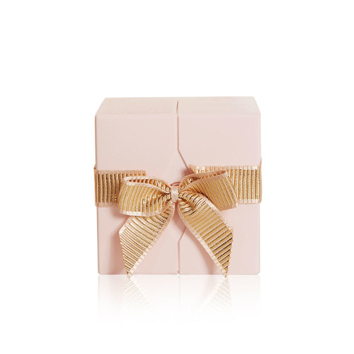 A beige-coloured gift wrapped with a bright gold ribbon. 