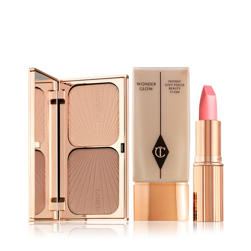 An open, mirrored-lid duo contour palette with a mirrored lid, foundation in a rectangular bottle with a gold-coloured lid and a bright pink lipstick in a gold-coloured tube.