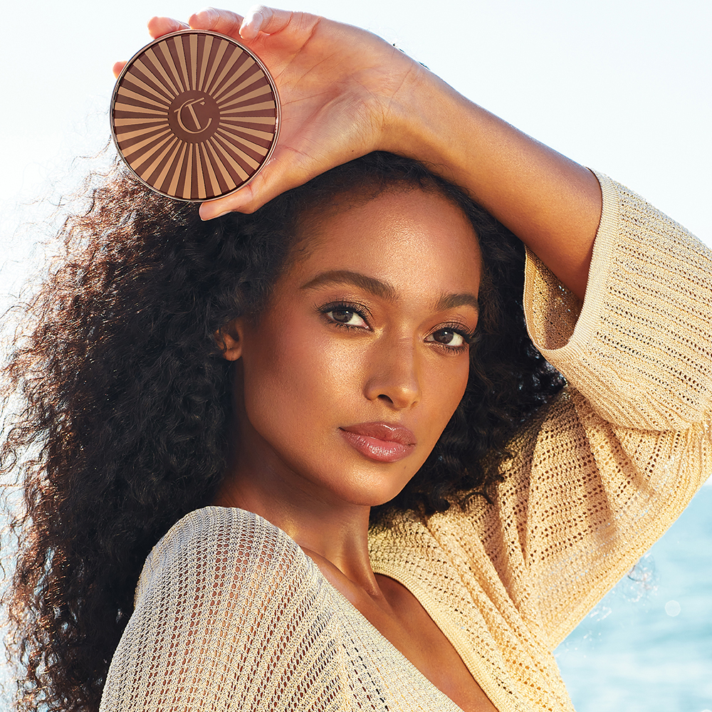 Mellie tient dans ses mains le bronzeur Sun-Kissed Glow de Charlotte's Beautiful Skin, une crème bronzante qui donne au teint une teinte bronzée et radieuse.