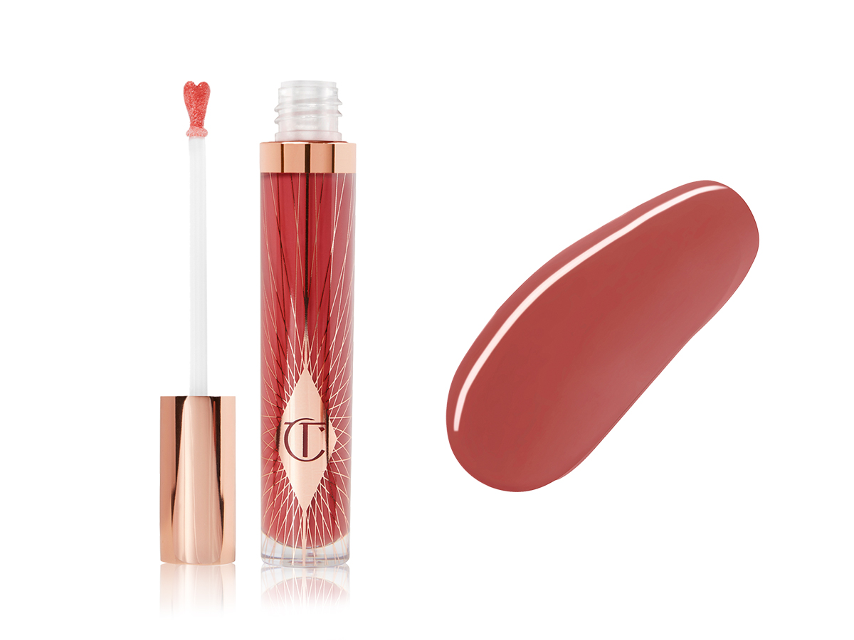 A lip gloss in a berry-rose shade with its heart-shaped applicator next to it along with its swatch. 