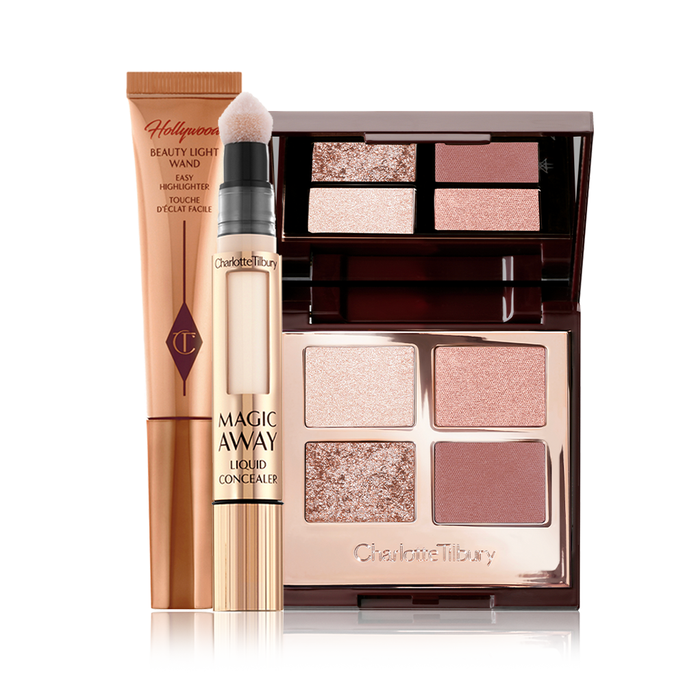 An open, mirrored-lid quad eyeshadow palette in shimmery and matte nude pink and beige shades with a cream concealer in golden packaging, and a highlighter wand in golden-bronze packaging. 