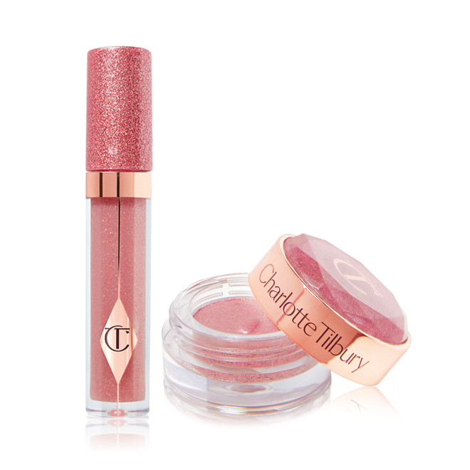 A shimmery nude-pink lip gloss in a glass tube with a glittery lid next to shimmery, cream eyeshadow in a nude-pink shade in a glass pot with its lid removed.