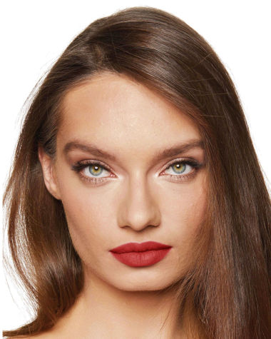 A medium-light-tone model with green eyes wearing a muted, matte brick red lipstick. 