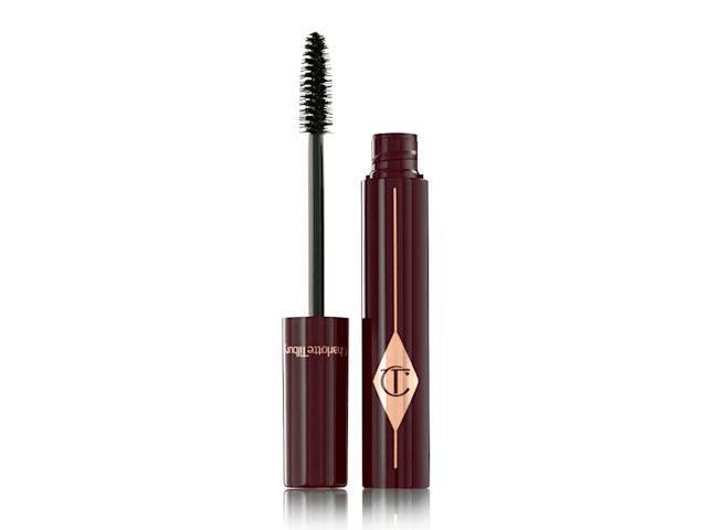 A black mascara in dark crimson packaging with its applicator next to it. 