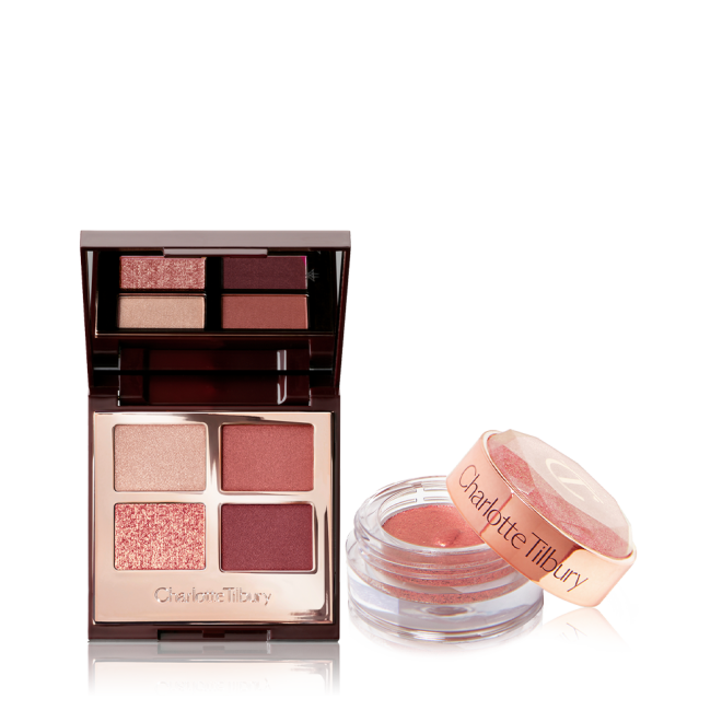 An open, mirrored-lid quad eyeshadow palette in berry-pink, red, and gold shades with a shimmery, cream eyeshadow in a berry-pink shade in a glass pot with its lid removed.