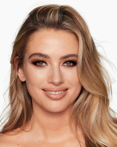 A light-tone blonde model with blue eyes wearing shimmery, copper and gold eyeshadow with rust and copper-coloured eyeliner on the upper lid and lower waterline. 