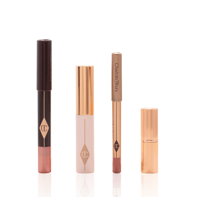 An unpacked makeup kit that includes an eyeshadow pencil in a rose gold shade, mascara, lip liner pencil in nude pink, and lipstick in a nude pink shade.