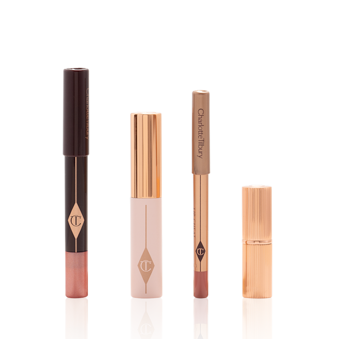 Pillow Talk On The Go products displayed An unpacked makeup kit that includes an eyeshadow pencil in a rose gold shade, mascara, lip liner pencil in nude pink, and lipstick in a nude pink shade.