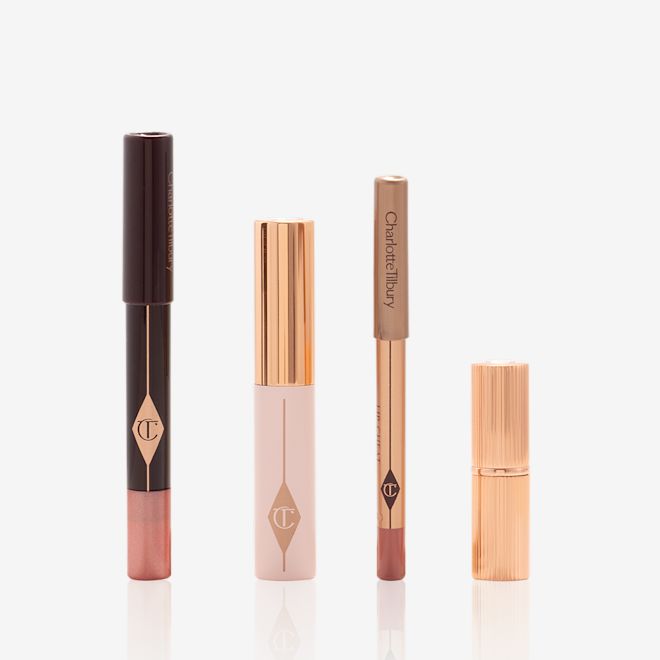 Pillow Talk On The Go products displayed An unpacked makeup kit that includes an eyeshadow pencil in a rose gold shade, mascara, lip liner pencil in nude pink, and lipstick in a nude pink shade.