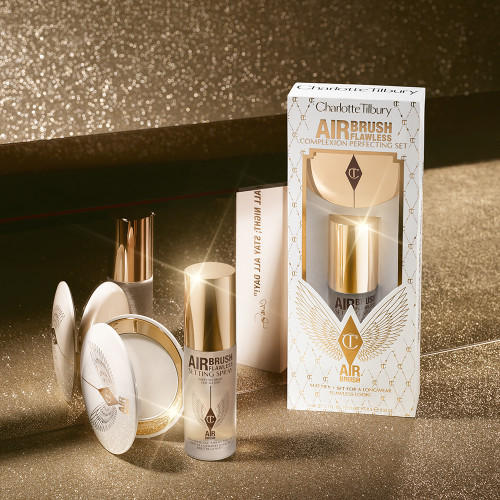 Setting spray in a clear bottle with a gold-coloured lid with a setting powder compact in gold-packaging with a mirrored-lid along with a white and pink-coloured packaging box.