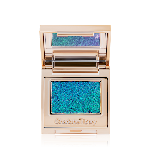 An open, single-pan eyeshadow with a mirrored lid in an iridescent duo-chrome purple and teal shade with very fine shimmer. 