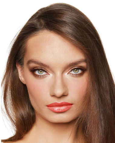 A medium-light-tone model with green eyes wearing smokey brown eye makeup with warm bronze and pink blush, and glossy terracotta lips.