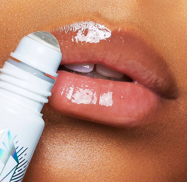 Model close up applying Charlotte's Magic Lip Oil Crystal Elixir